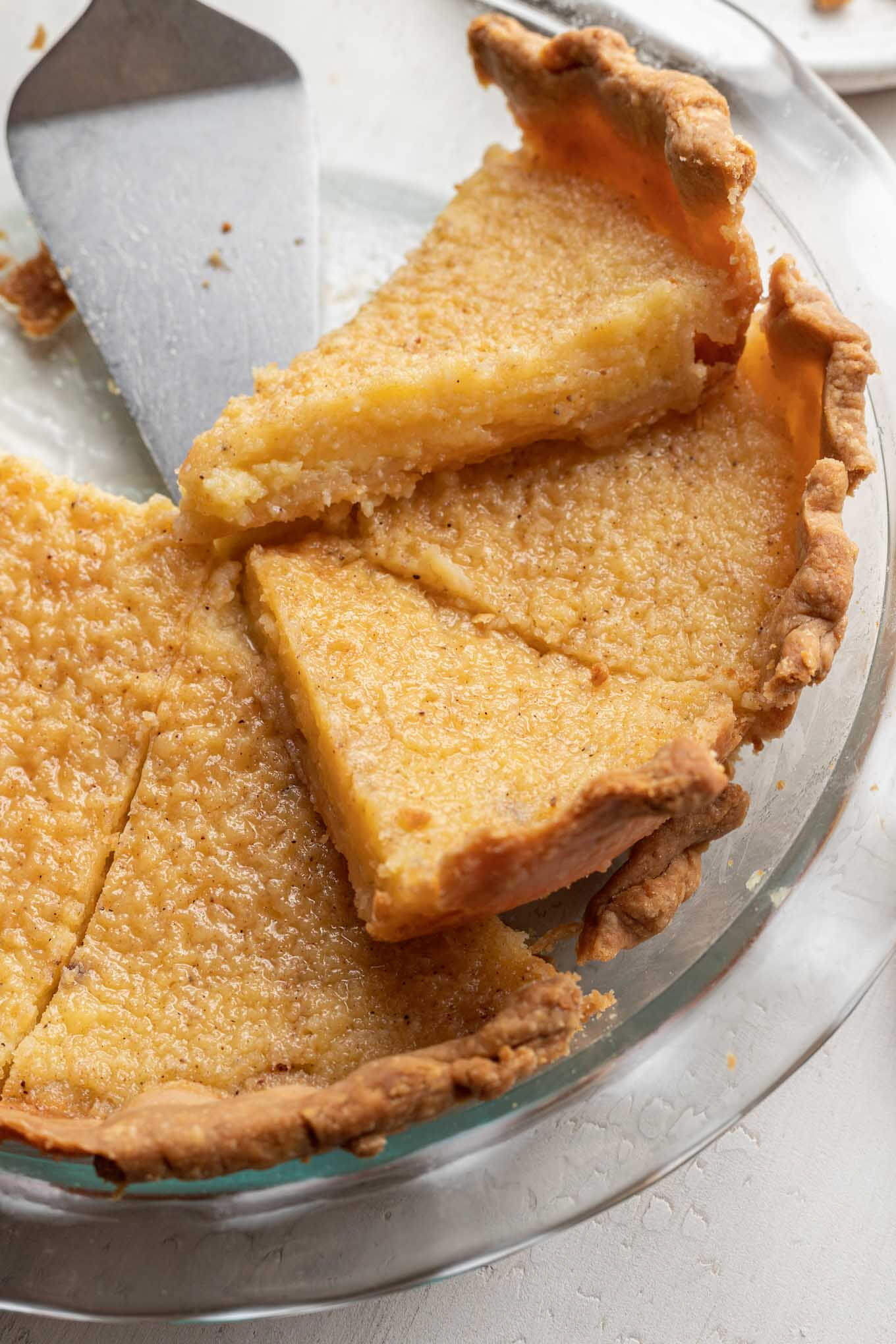 A sliced buttermilk pie in a glass pie plate. 