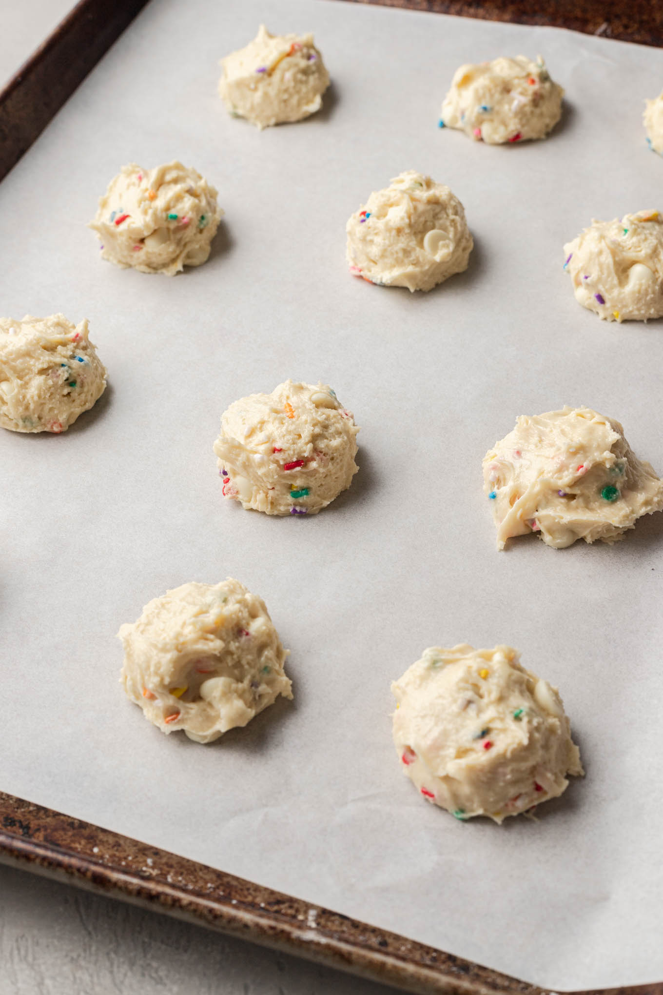 Cookie dough balls on a parchment paper-lined baking sheet. 