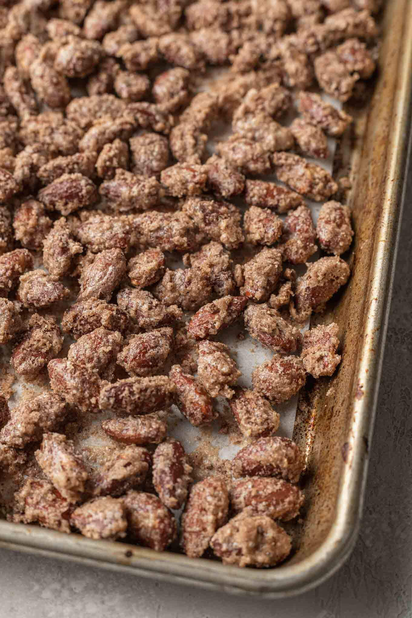 Cinnamon candied almonds on a parchment paper-lined baking sheet. 