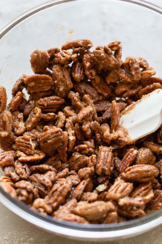 A glass bowl filled with pecan halves coated in the cinnamon sugar mixture.