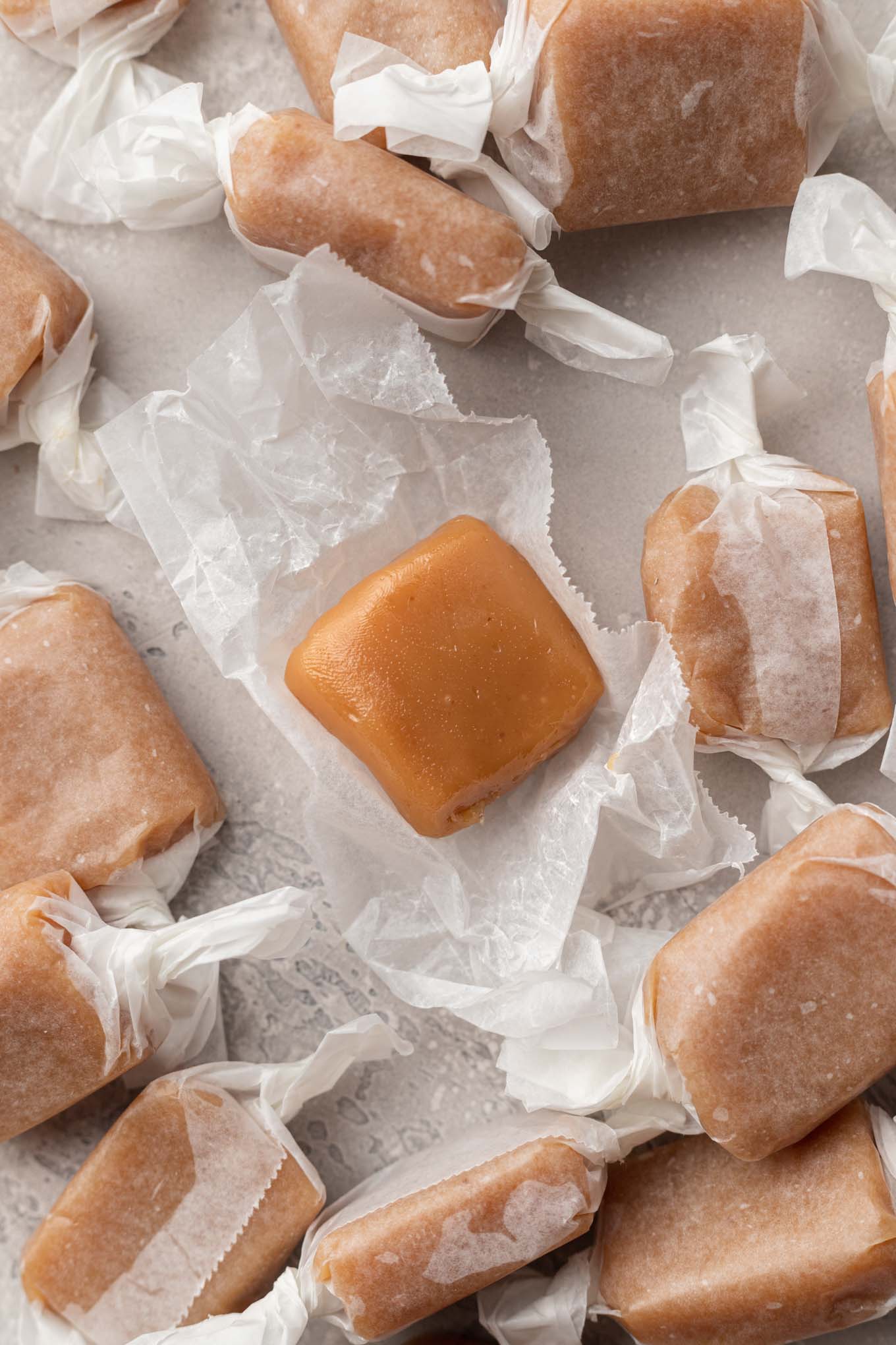 A close up view of an unwrapped soft caramel, surrounded by additional caramels. 