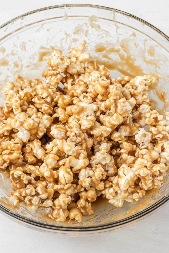 Popcorn coated in caramel sauce in a large glass mixing bowl.