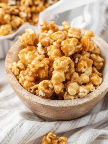 A small wooden bowl filled with caramel corn.