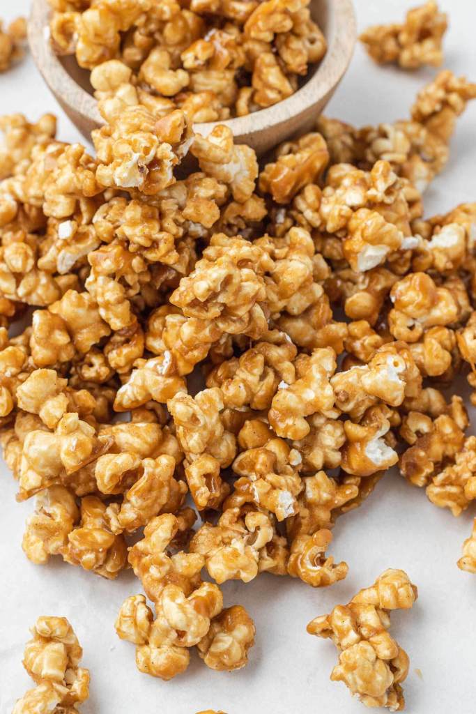 A mound of homemade caramel popcorn next to a small dish of it. 