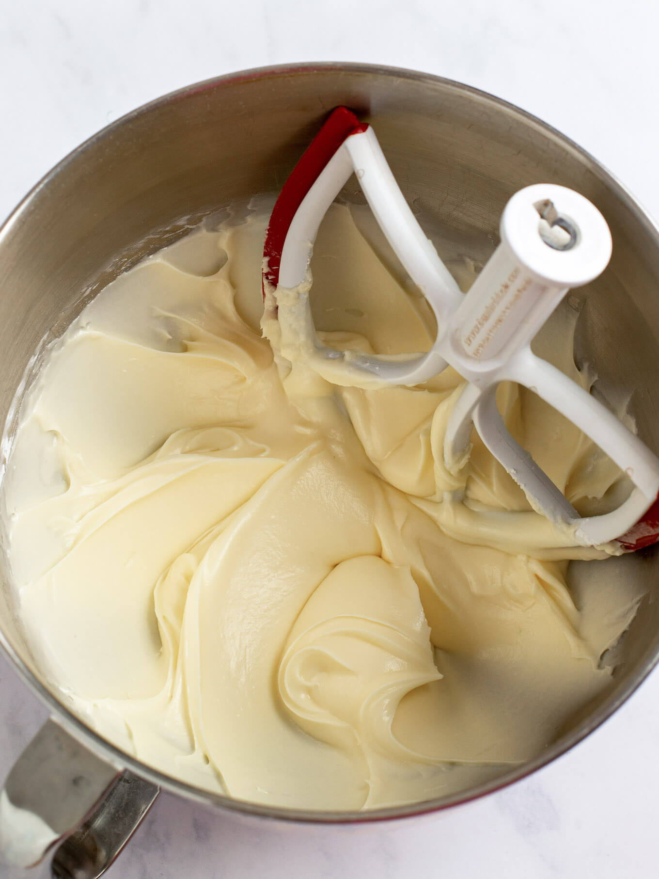 Cream cheese frosting fully mixed together in the bowl of a stand mixer.