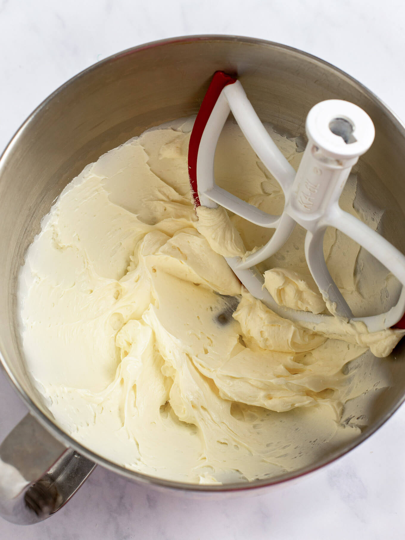 Cream cheese and butter mixed together in the bowl of a stand mixer.