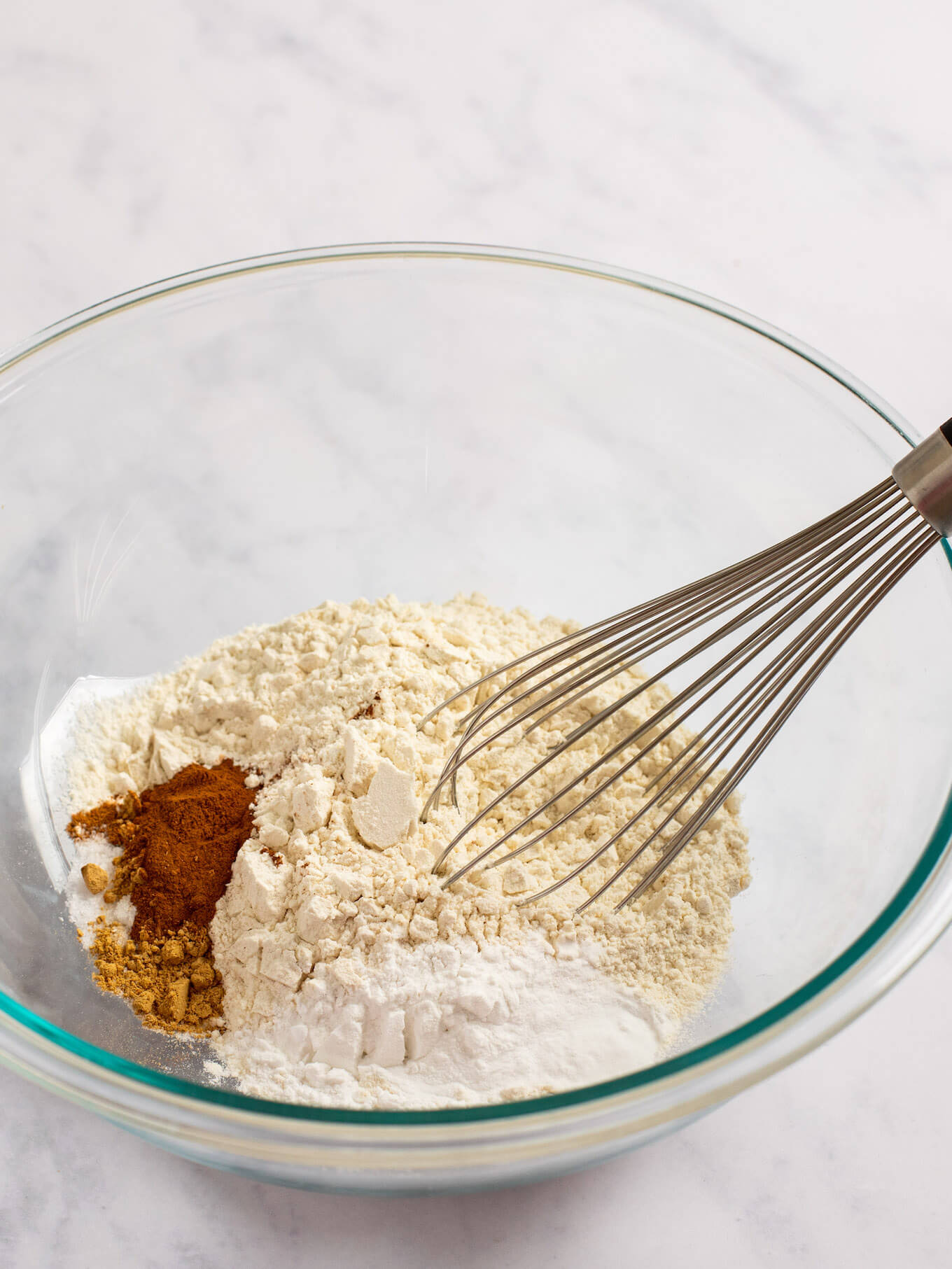 Flour, spices, baking powder, baking soda, and salt in a glass mixing bowl.