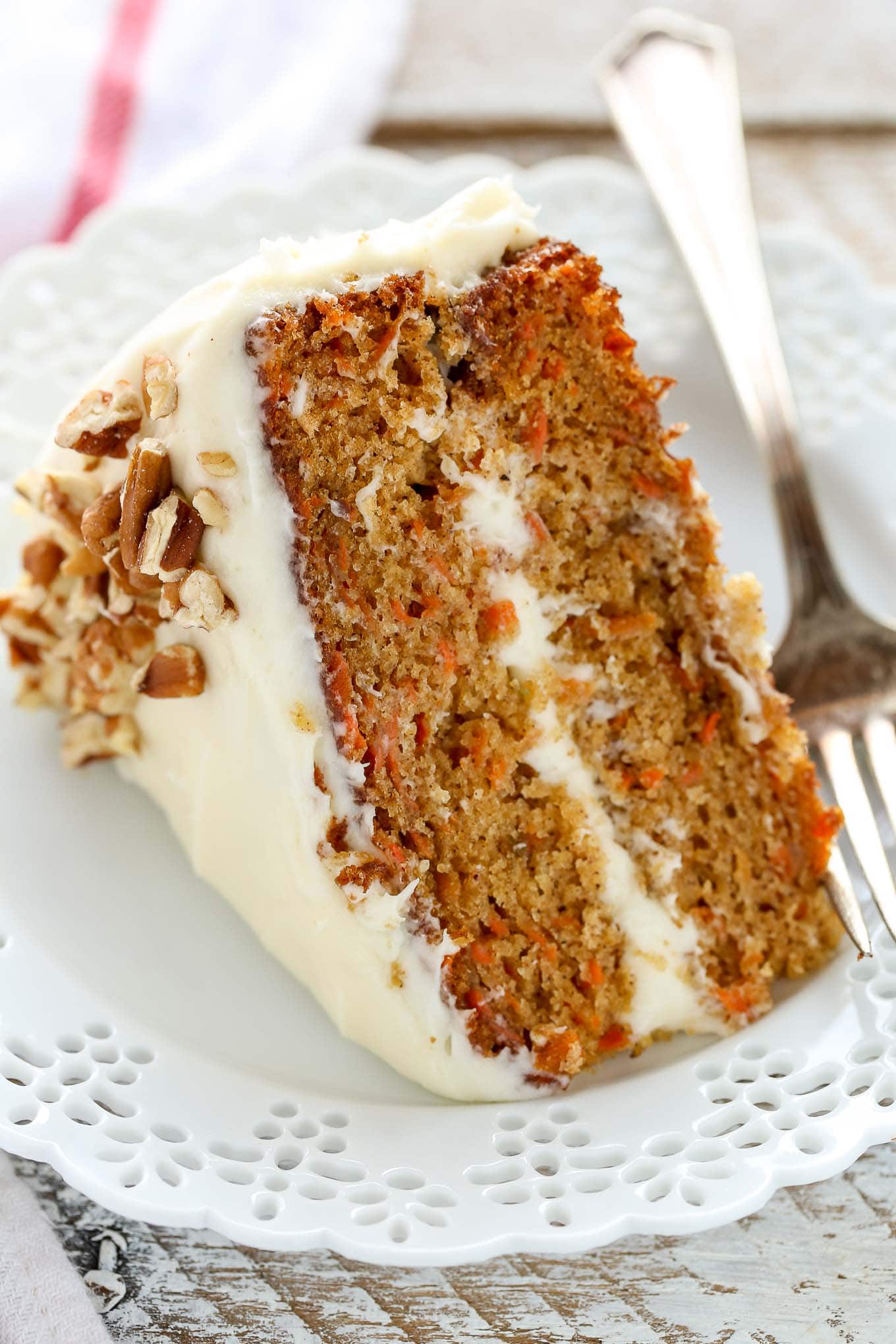 A close up of a slice of carrot cake on a decorative white plate.