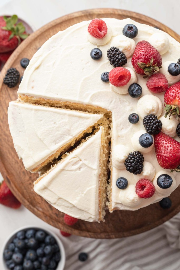 An overhead view of a Chantilly berry cake, with two slices cut out. 