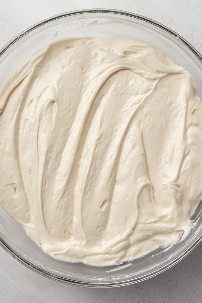 An overhead view of vanilla cake batter in a glass mixing bowl.