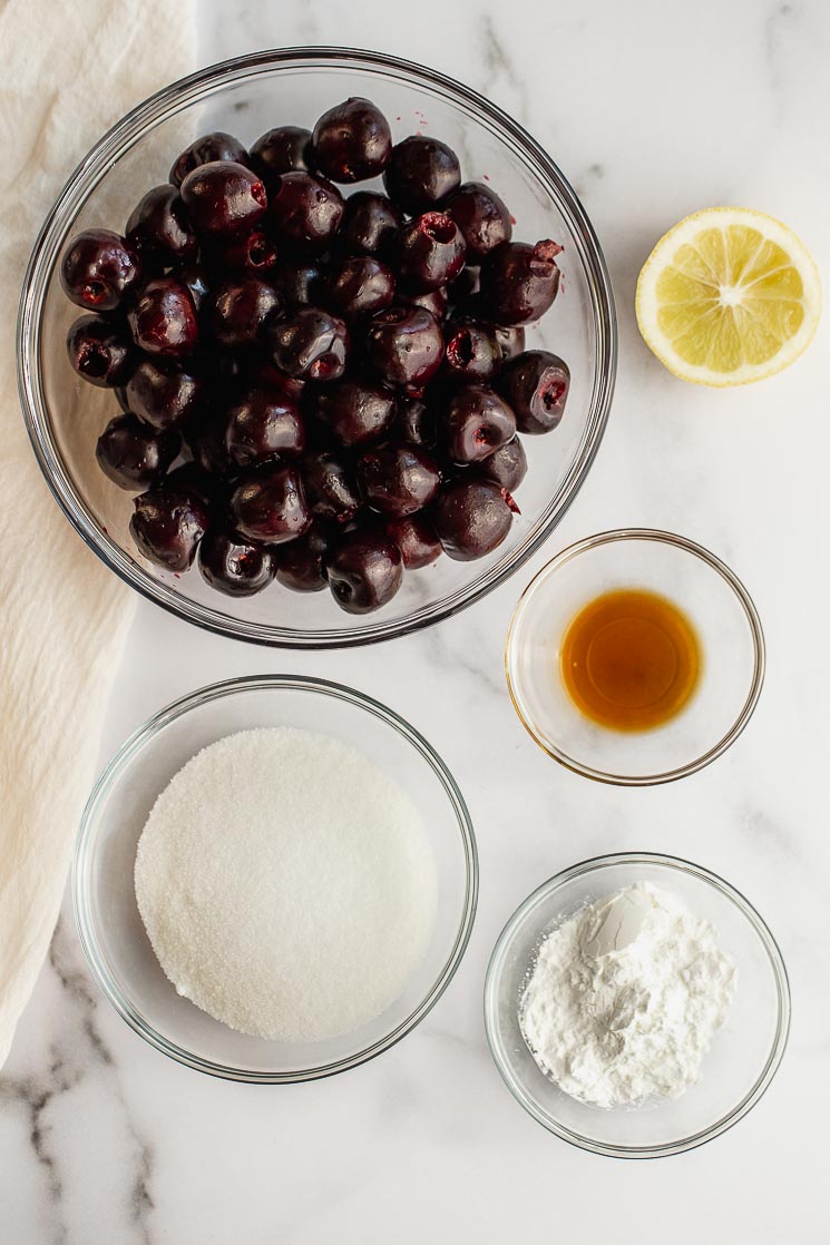 The ingredients for cherry pie filling on a marble surface.