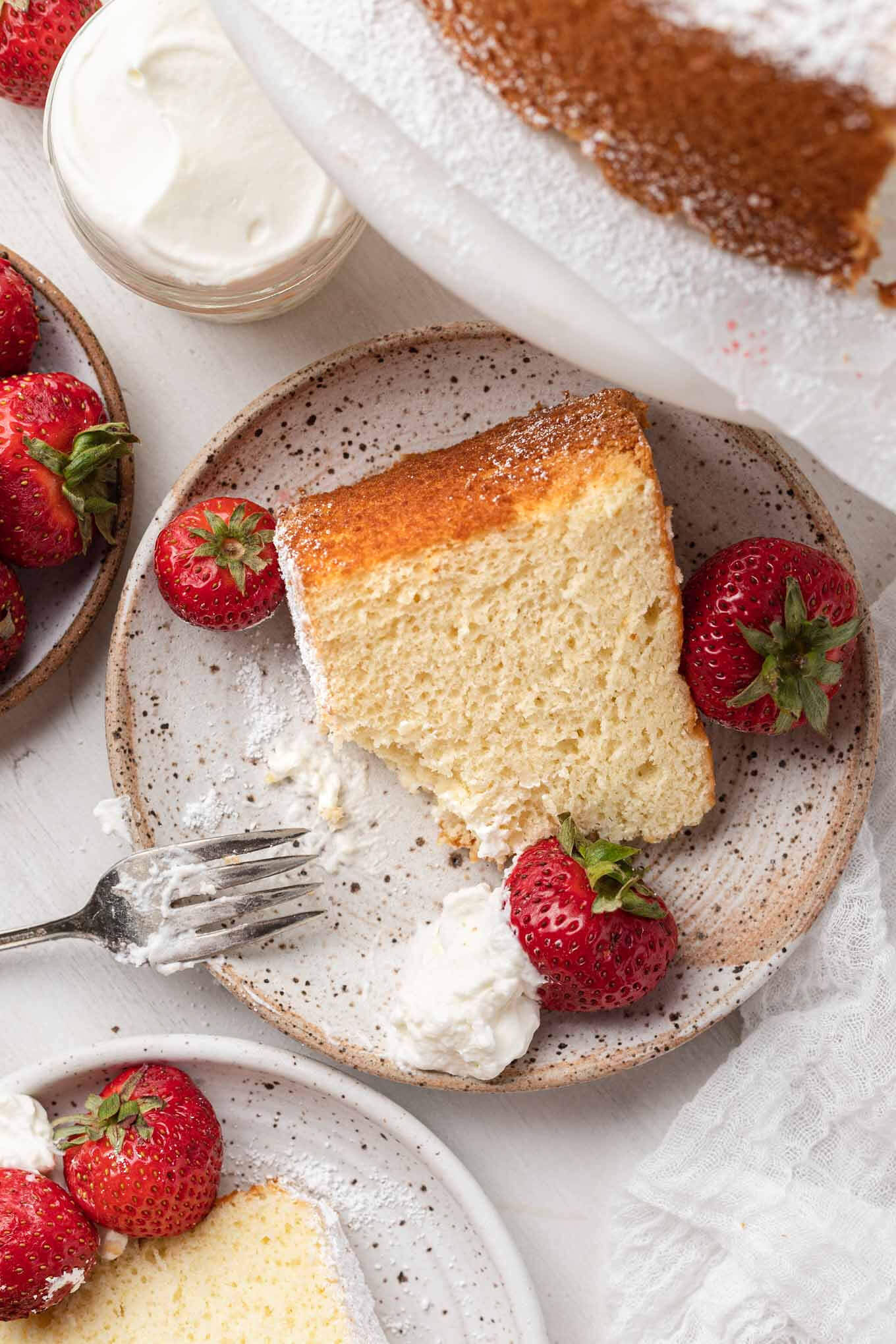 An overhead view of chiffon cake slices with whipped cream and berries. 