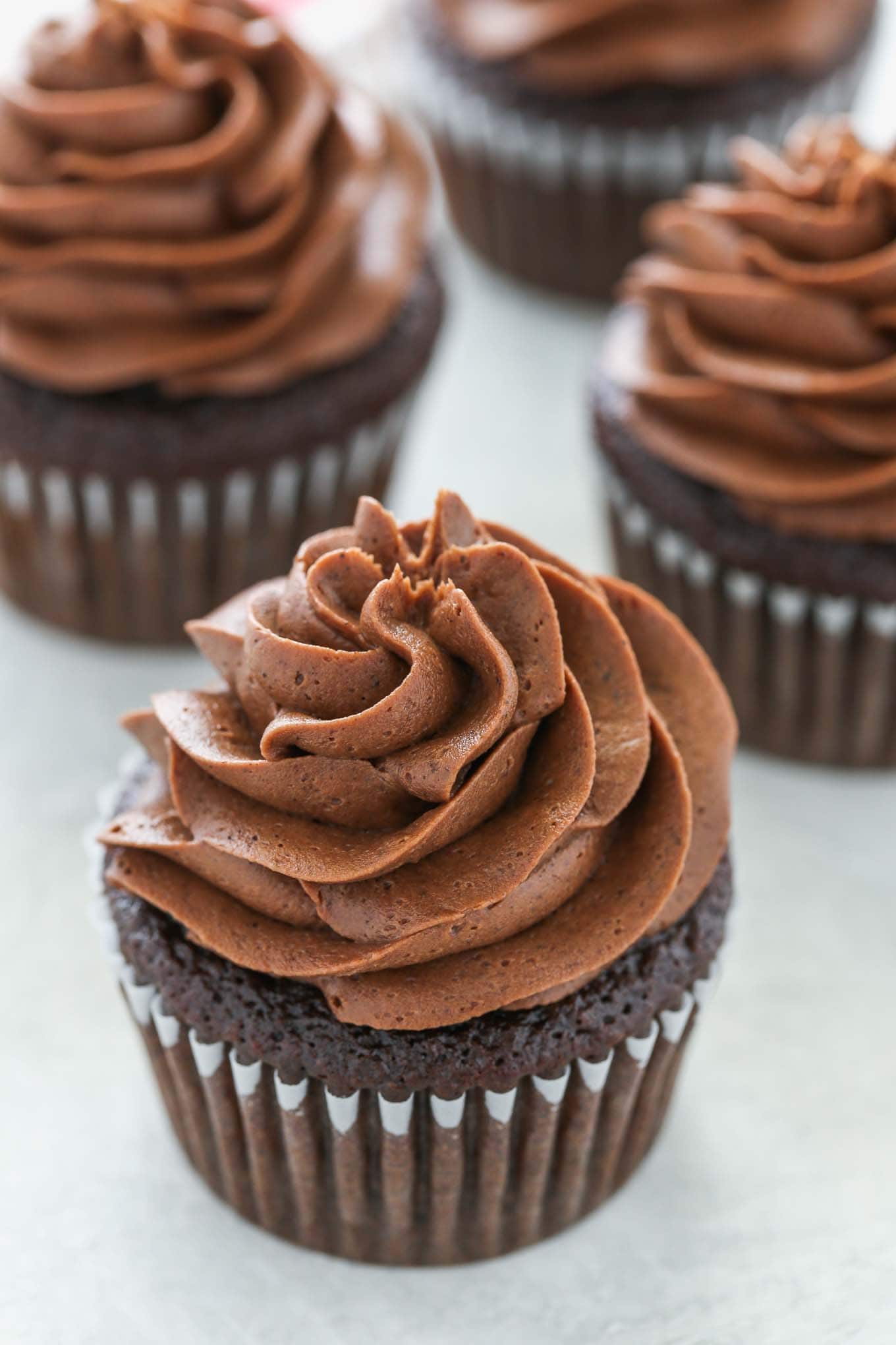 Four chocolate cupcakes topped with homemade chocolate frosting. 