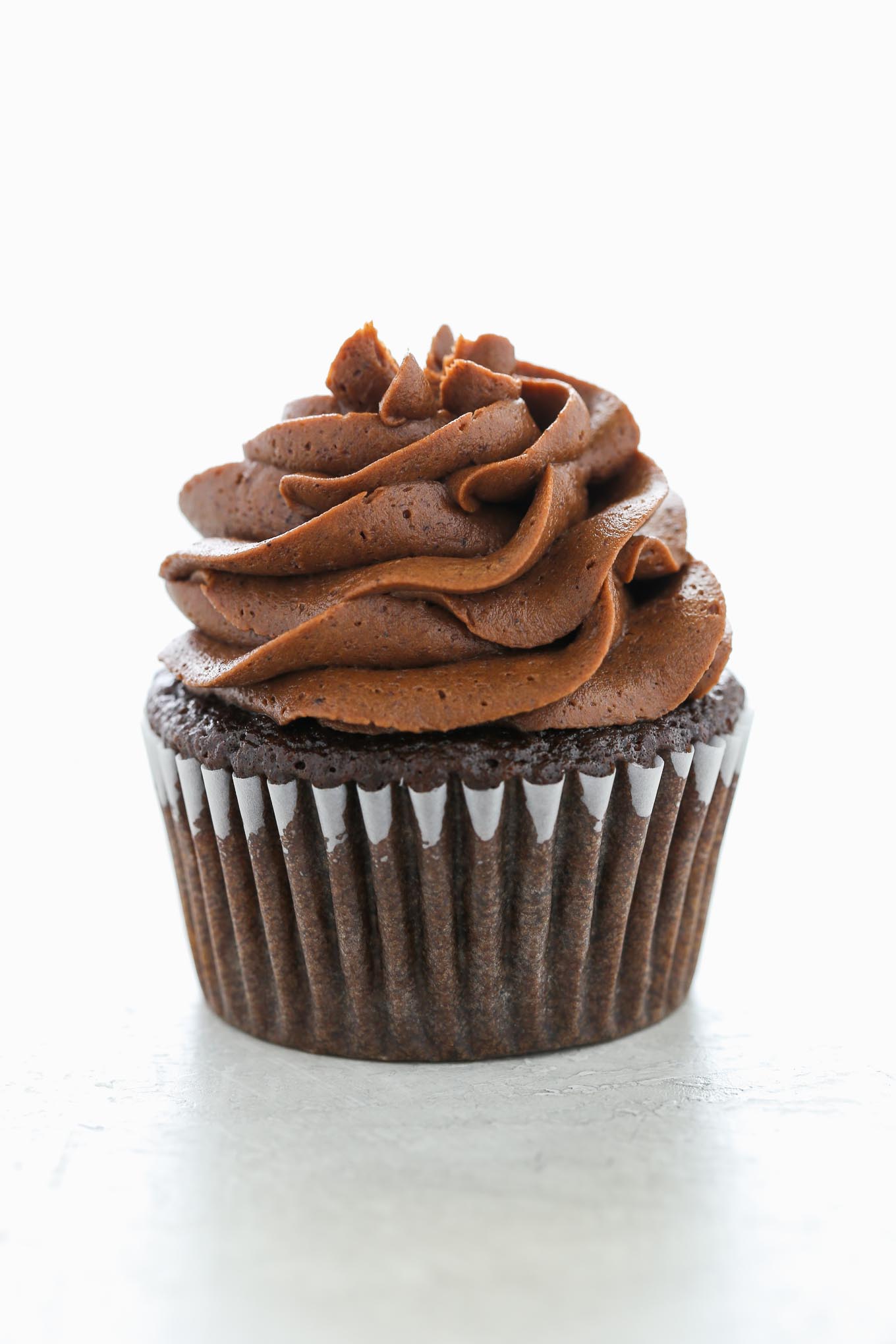 A single chocolate cupcake topped with a swirl of chocolate buttercream frosting. 