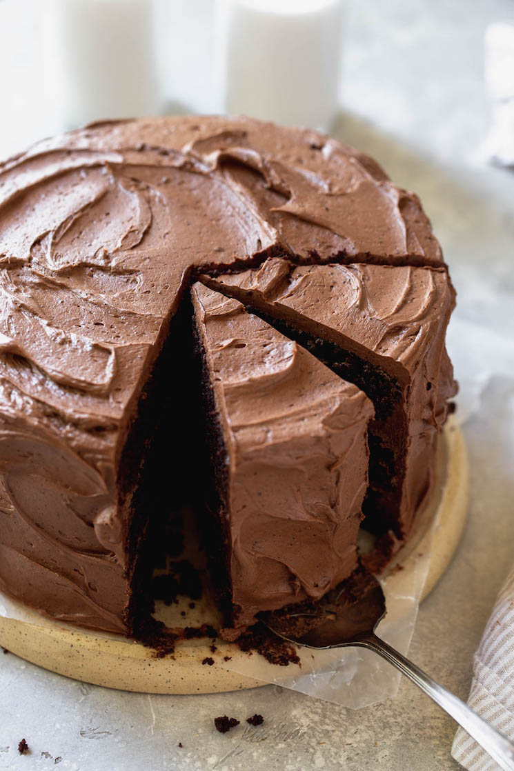 A chocolate cake sitting on a round board with a couple of pieces sliced.