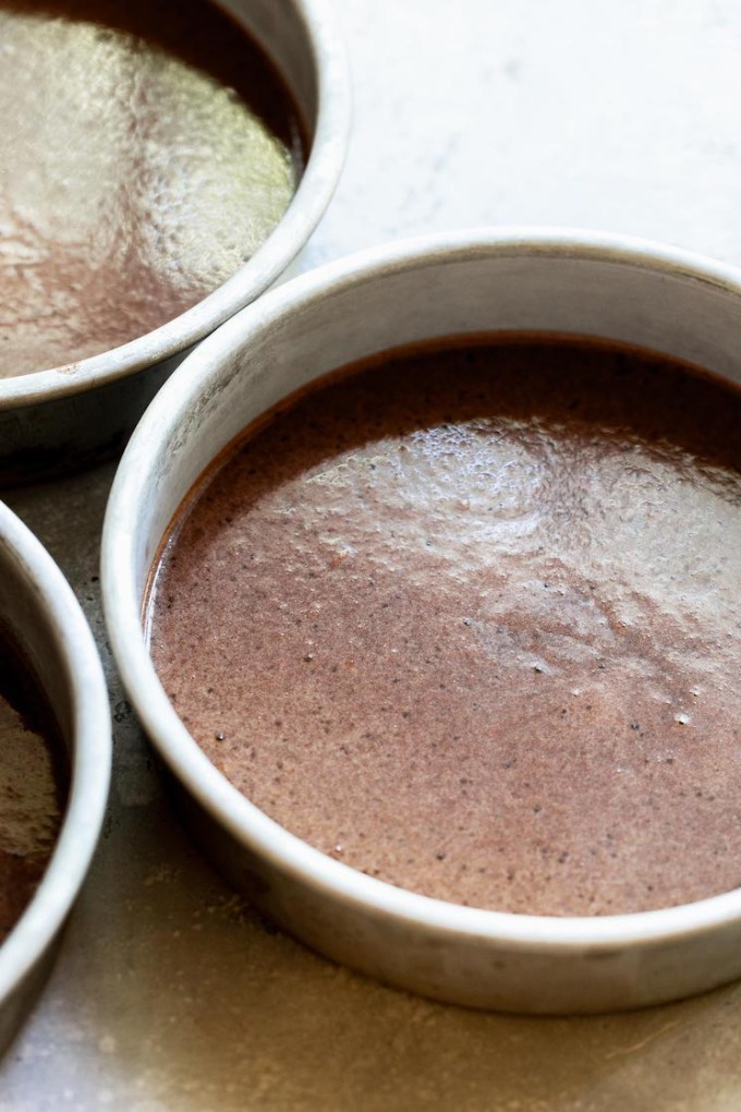 The cake batter divided into three round cake pans.