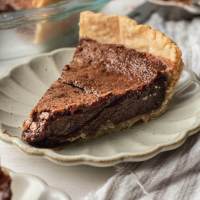 A slice of chocolate chess pie on a scalloped plate.