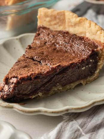 A slice of chocolate chess pie on a scalloped plate.