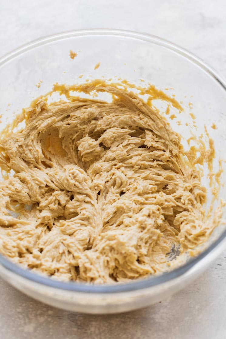 A glass mixing bowl holding the wet ingredients needed to make cookie cake.