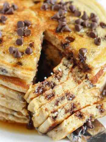 A stack of Chocolate Chip Greek Yogurt Pancakes. A bite has been cut out.