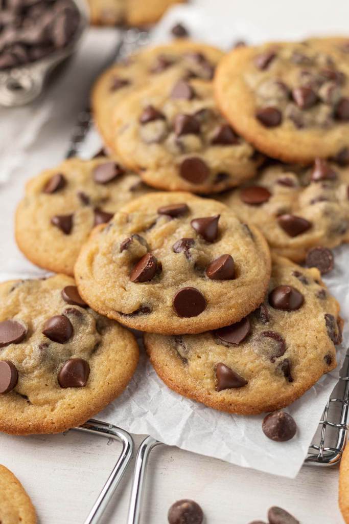 A pile of pudding cookies on a parchment-lined wire cooling rack. 