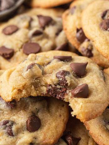 Several chocolate chip pudding cookies stacked on top of each other. The top cookie has a bite missing.