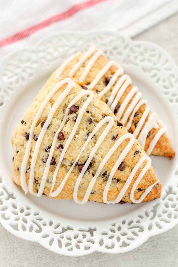 Two glazed chocolate chip scones on a white plate. 