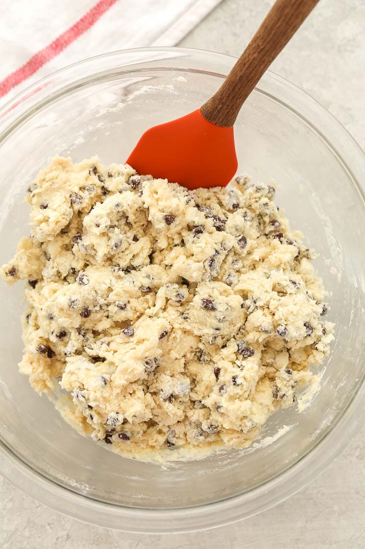 Homemade chocolate chip scone batter in a glass mixing bowl with a spatula. 