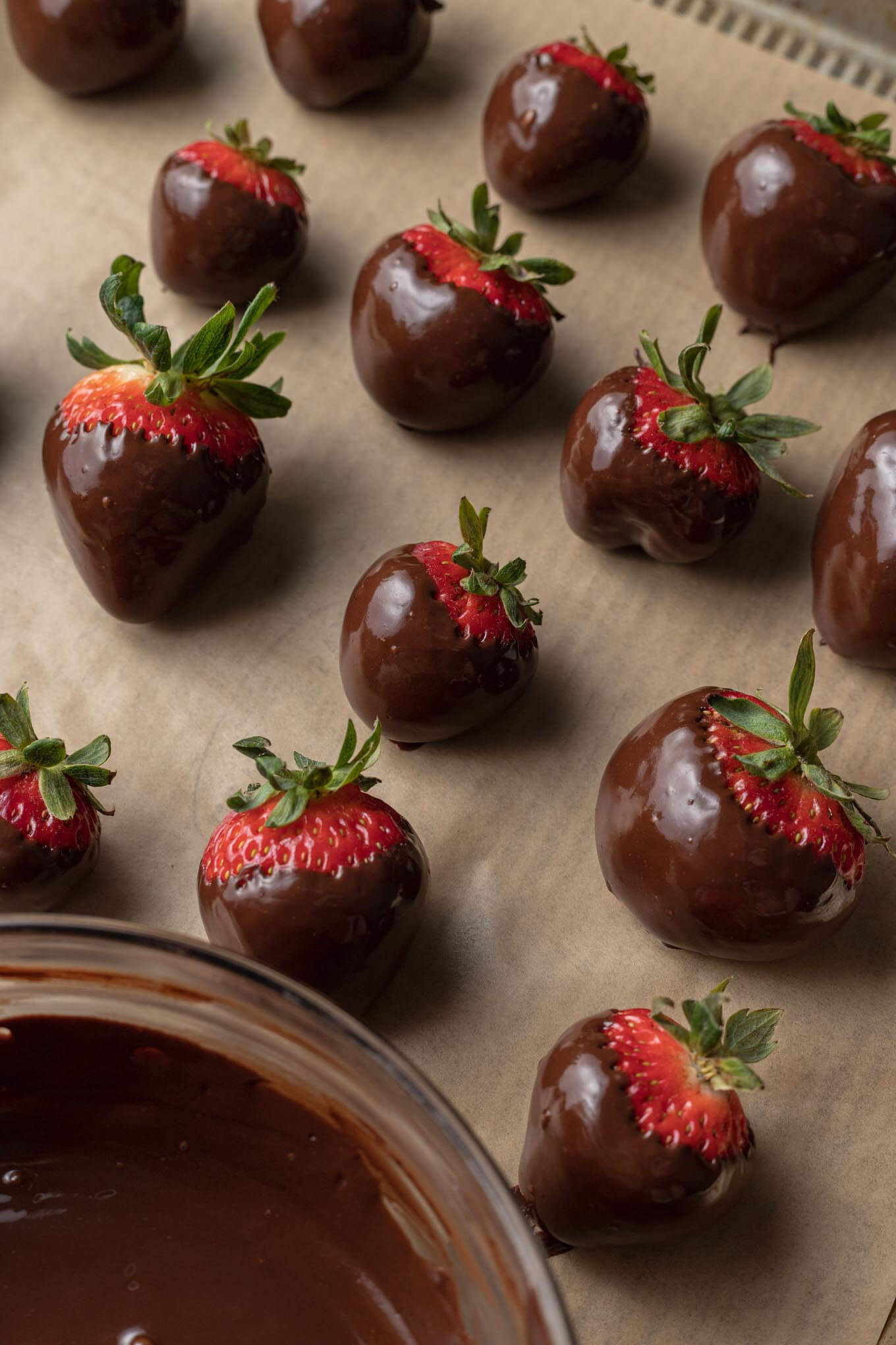 Chocolate covered strawberries on a parchment paper lined baking tray.