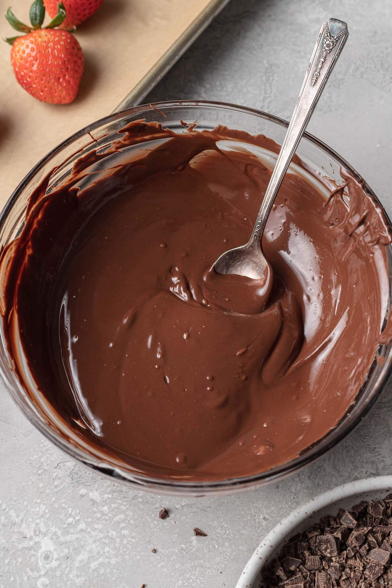 A glass mixing bowl containing tempered chocolate.