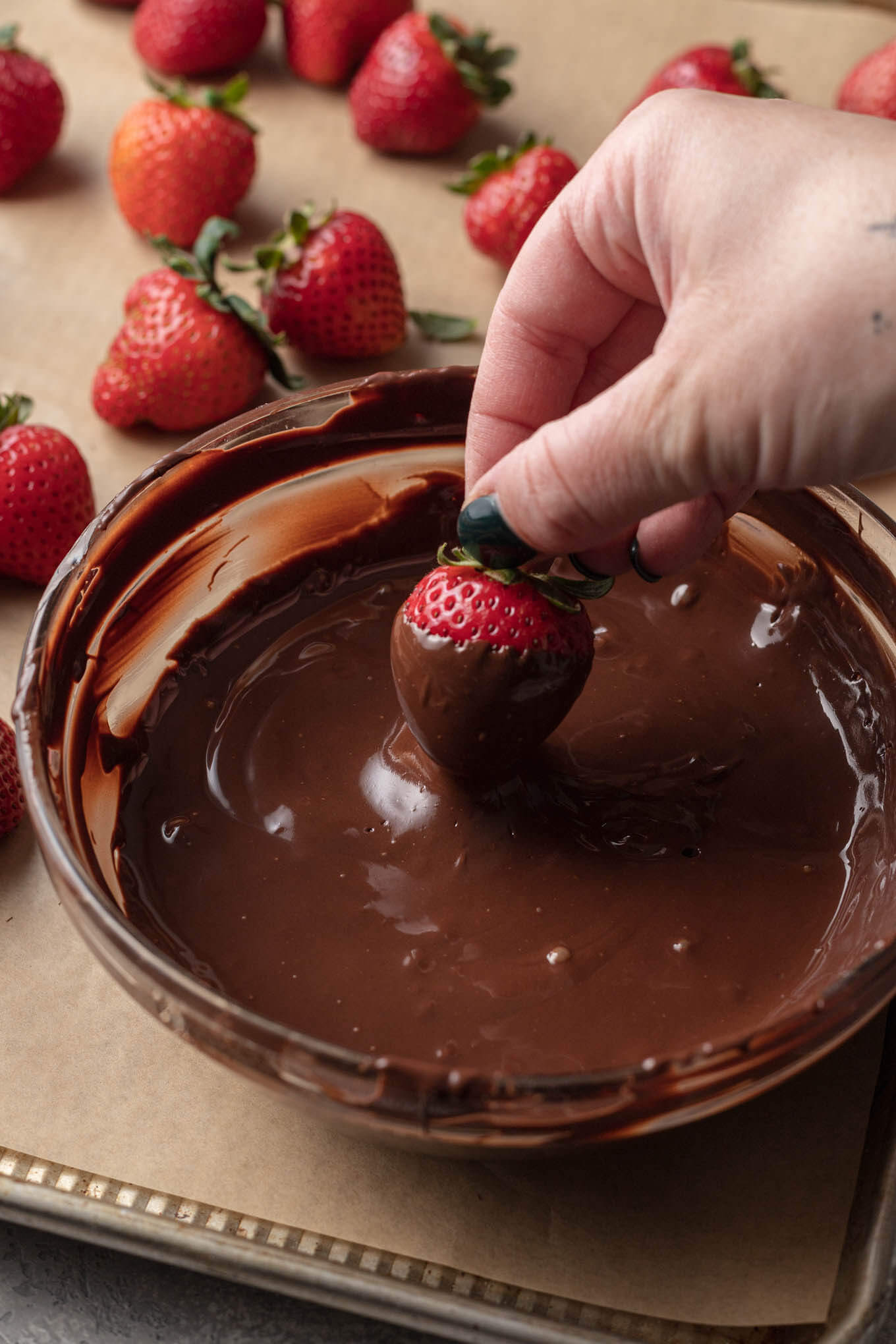 A fresh strawberry being coated in tempered chocolate.