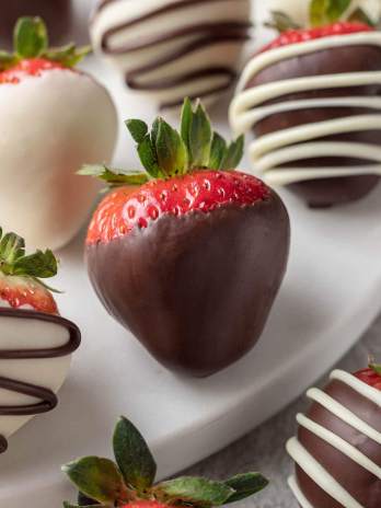 Several chocolate covered strawberries on a round piece of marble.