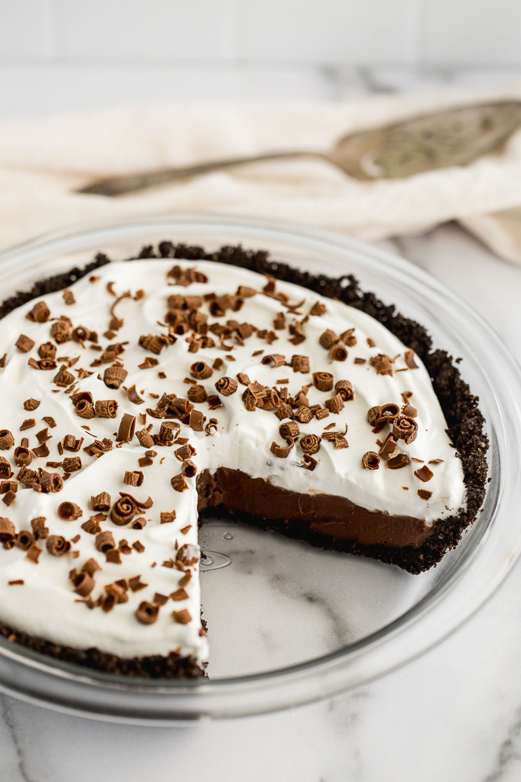 A chocolate cream pie with a slice taken out of it.