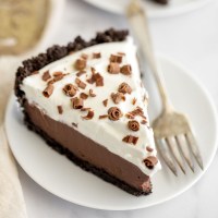 A slice of chocolate cream pie on a white plate.