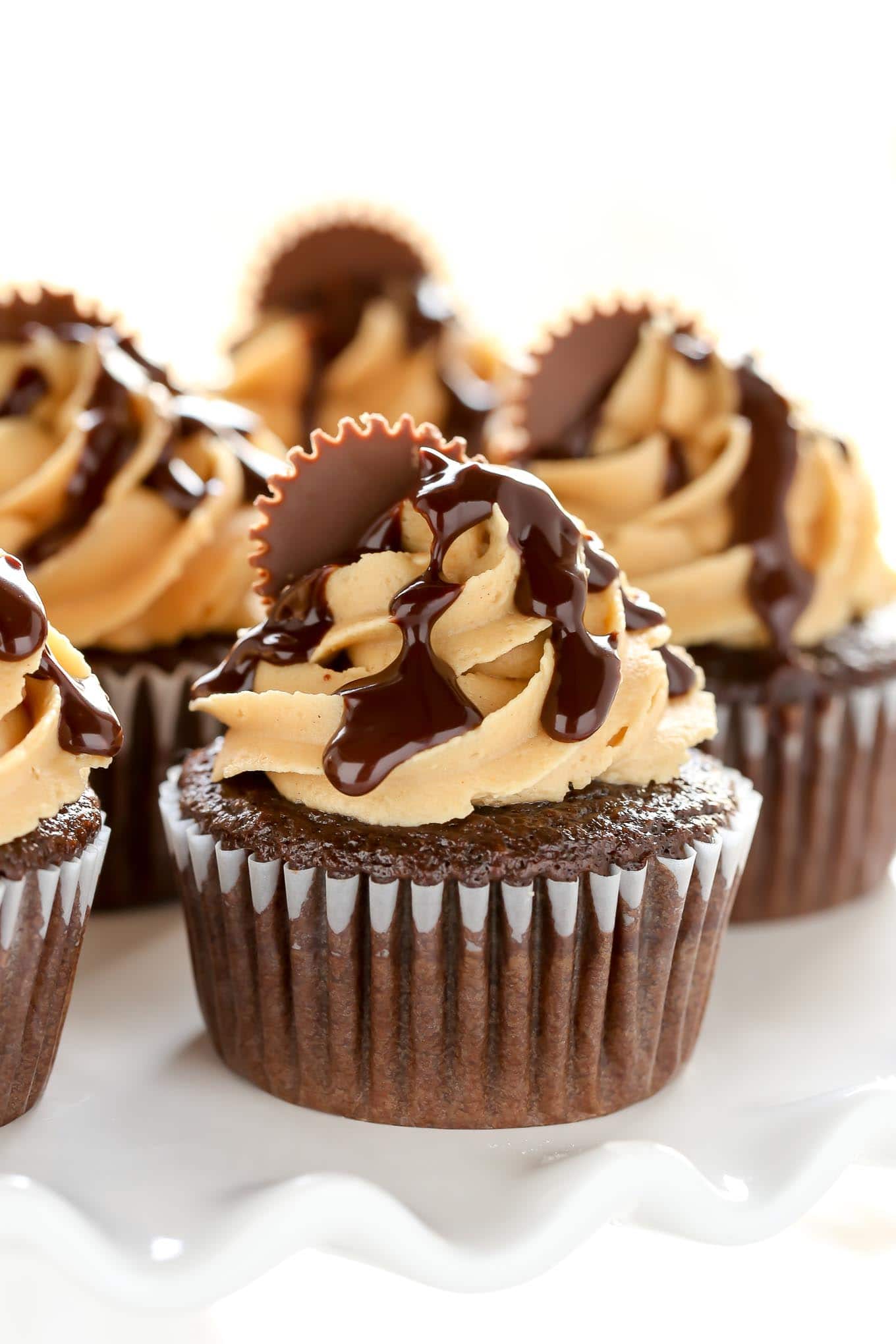 Close up of chocolate peanut butter cupcakes on a white cake stand. 