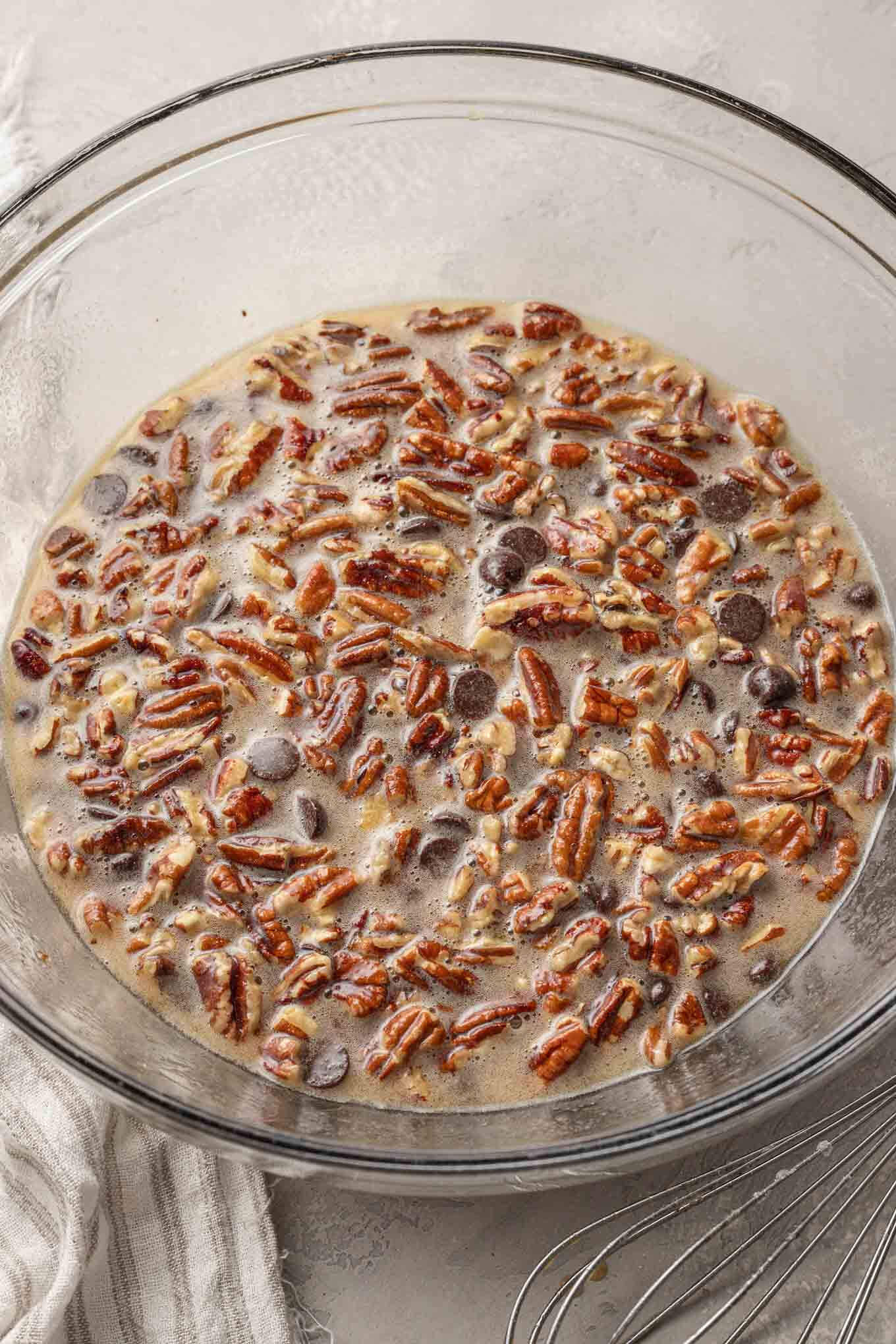 An overhead view of pecan chocolate pie filling in a glass mixing bowl. 
