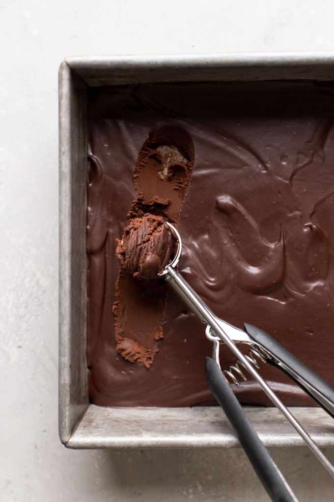 Chocolate truffle mixture being scooped from a baking pan.