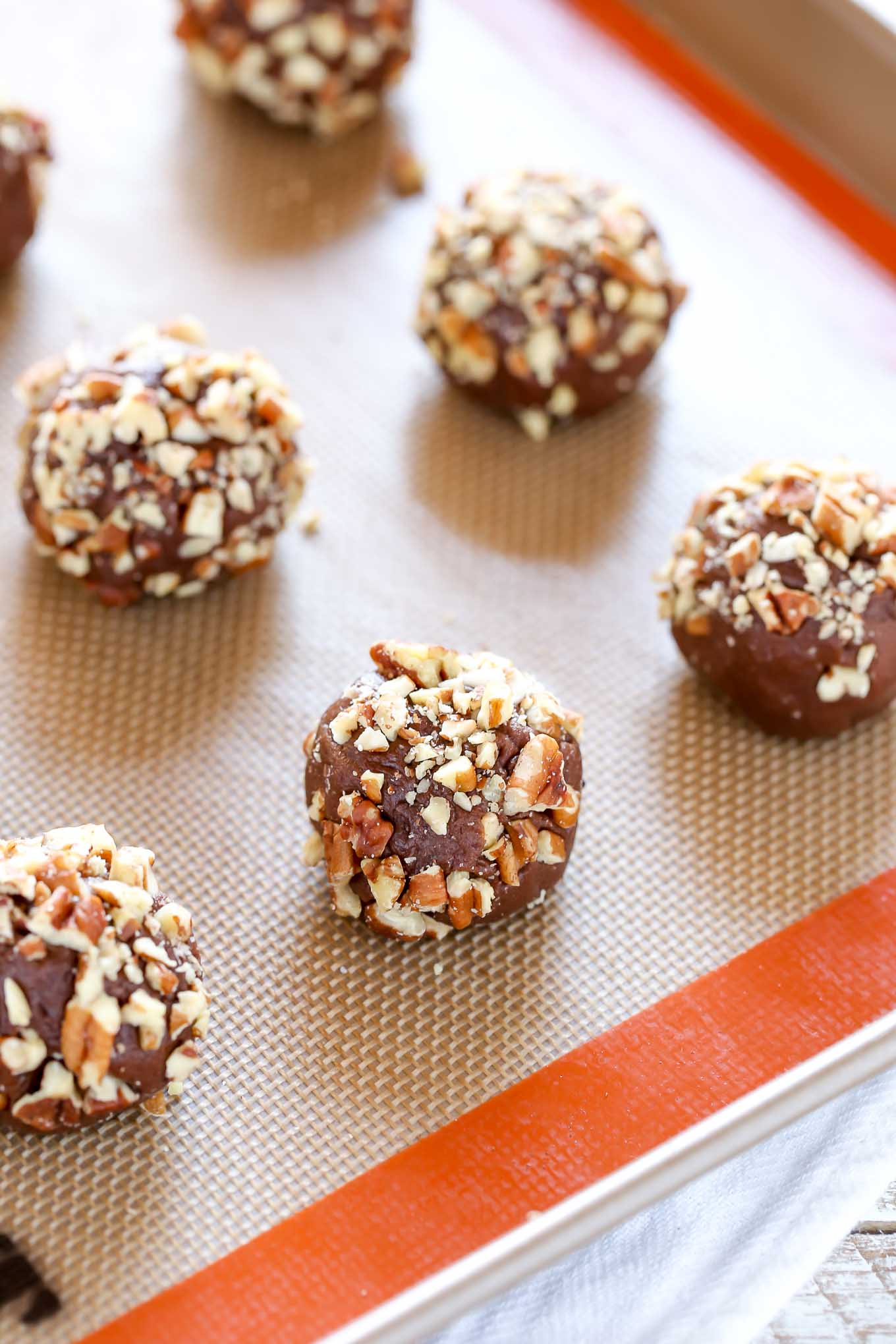 Unbaked balls of turtle cookie dough on a Silpat-lined baking tray. 