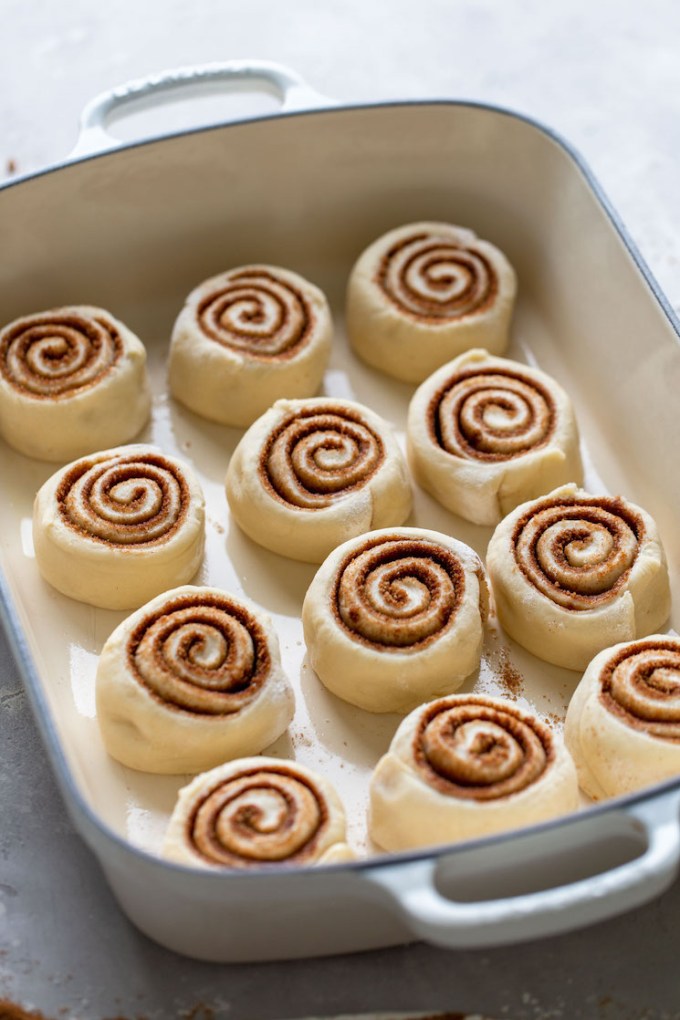 Cinnamon rolls that have been cut and placed into a baking pan.