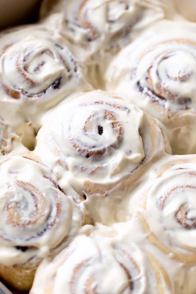 A pan of baked cinnamon rolls topped with cream cheese frosting.