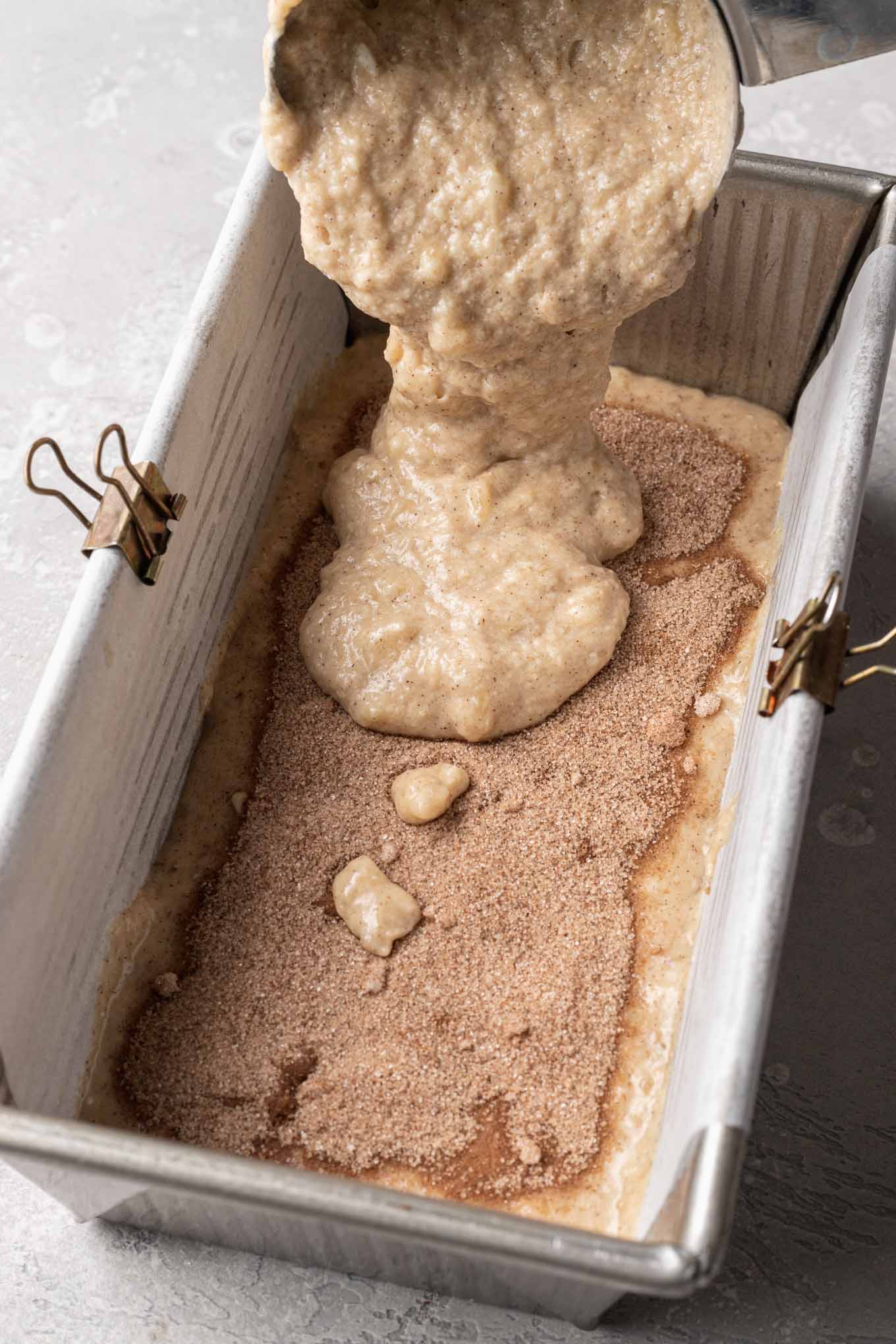 More banana bread batter being added on top of the cinnamon sugar filling.