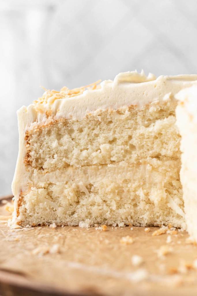 A side view of a coconut cake that's been sliced to show the interior. 