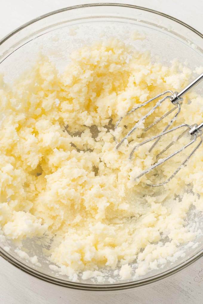 An overhead view of creamed butter and sugar in a glass mixing bowl.