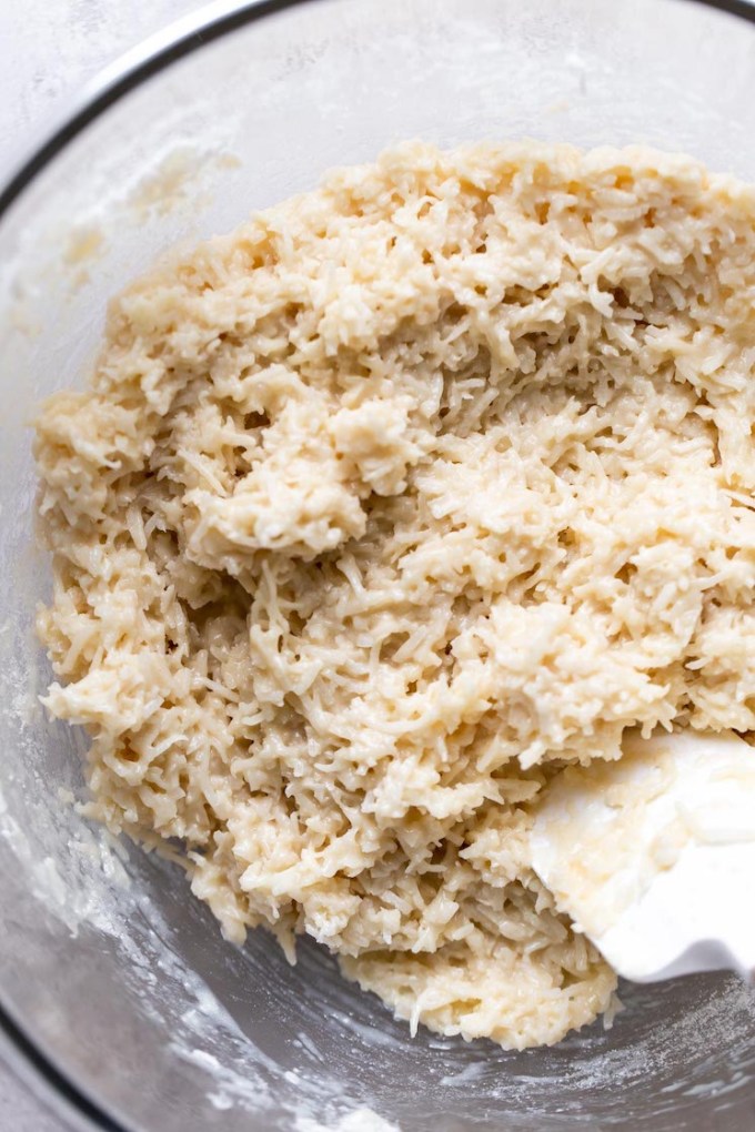 Coconut macaroon dough in a glass mixing bowl with a rubber spatula.