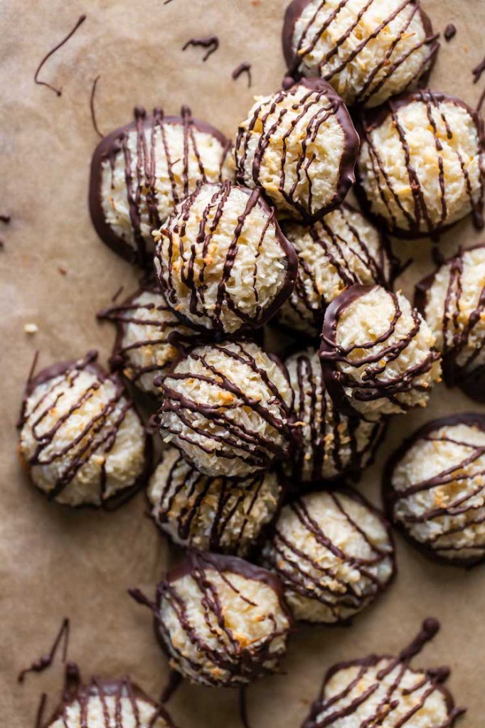 A pile of macaroon cookies drizzled with chocolate on parchment paper. 