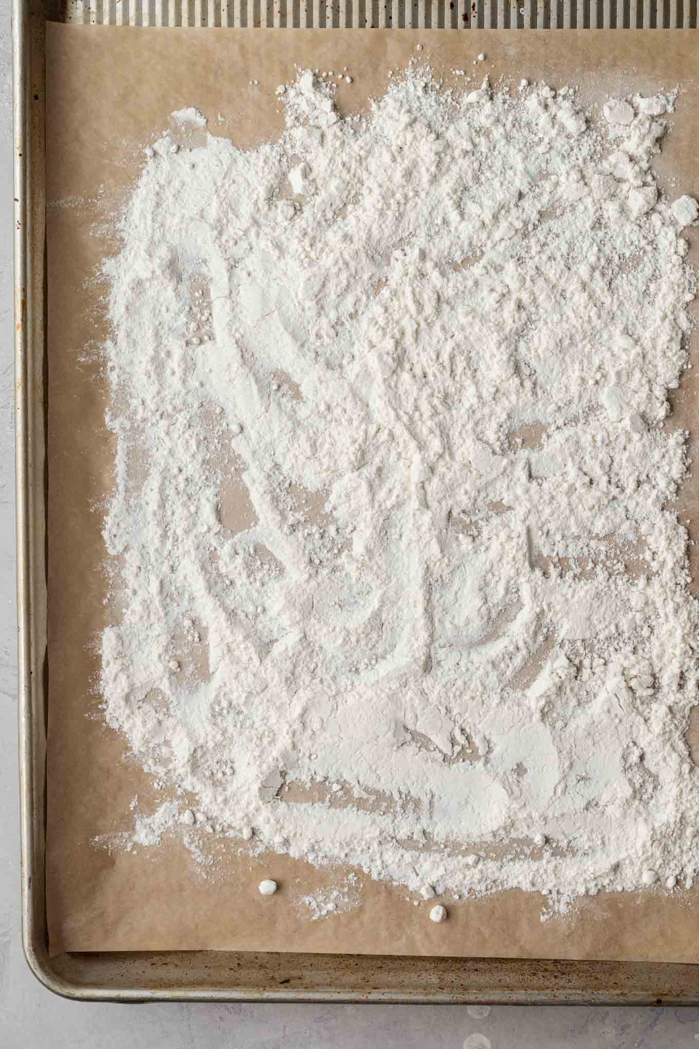 An overhead view of flour on a baking sheet. 