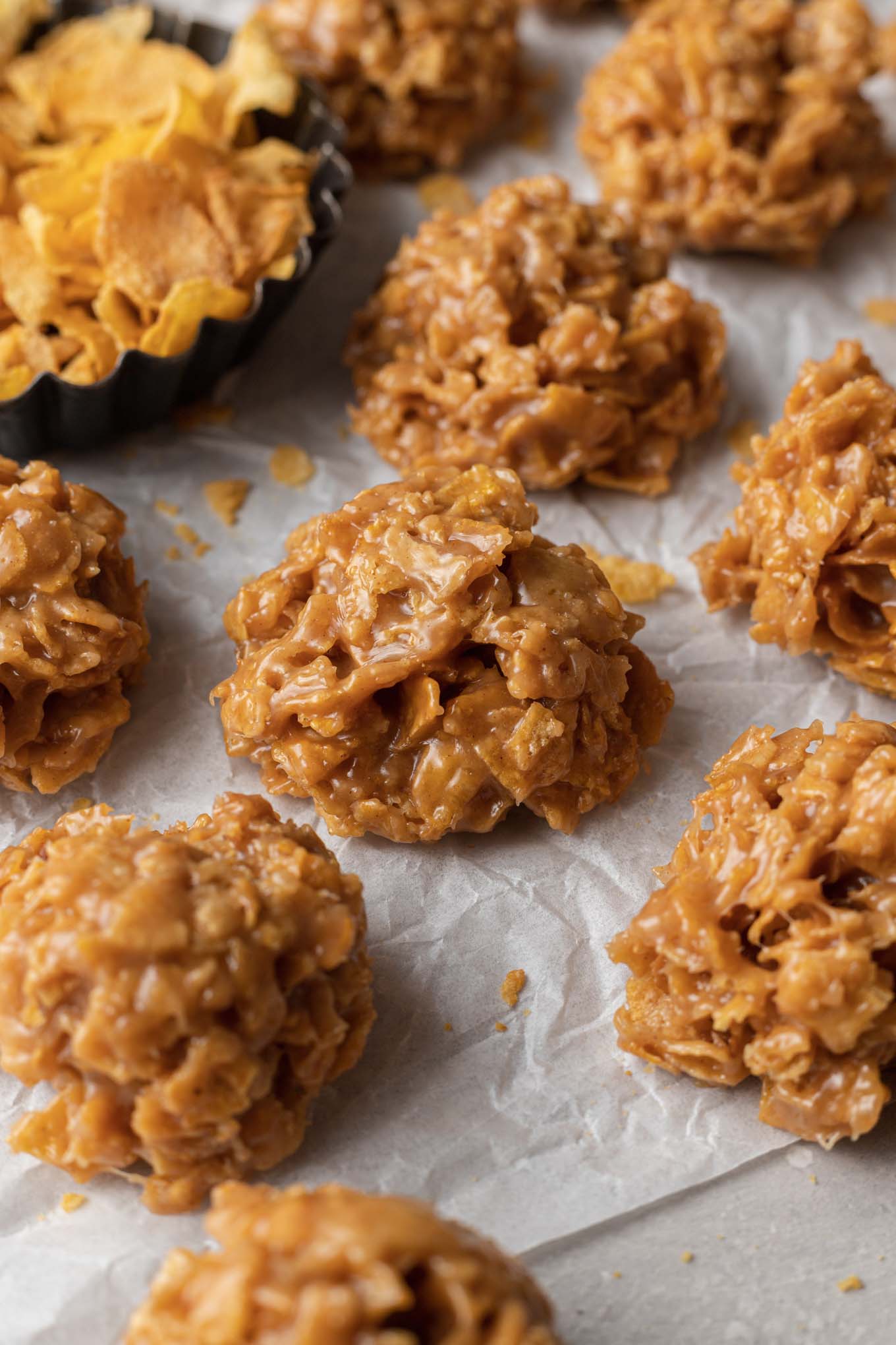 A close-up view of cornflake cookies on parchment paper. 