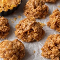 Several cornflake cookies on a piece of parchment paper.