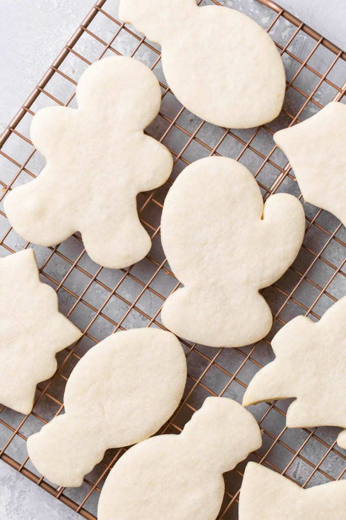 A cooling rack holding baked cut-out sugar cookies that are cooling before icing them.