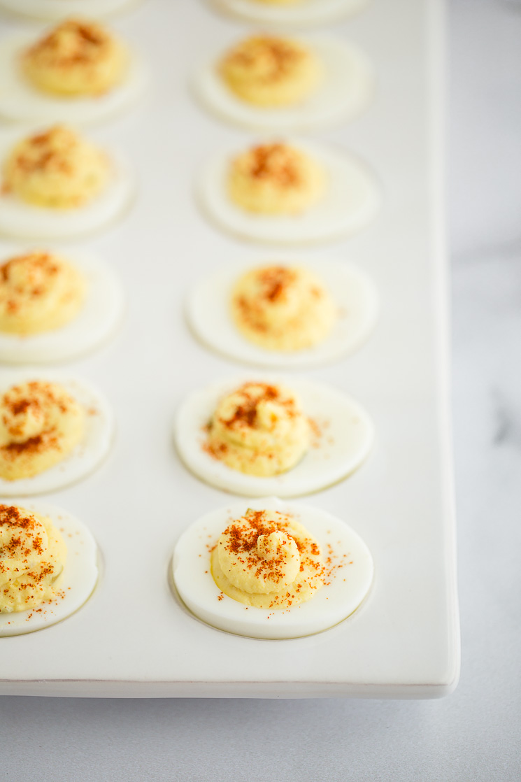 Deviled eggs topped with smoked paprika in a deviled egg tray.